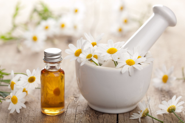 17665524 - essential oil and camomile flowers in mortar