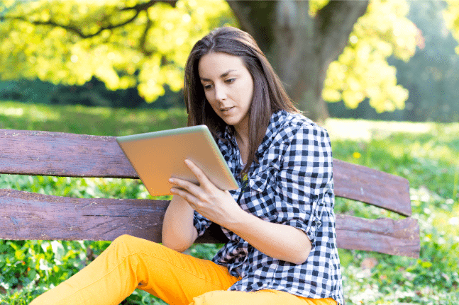 Young woman using digital tablet in park